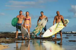 a group of people on a beach holding a surf board